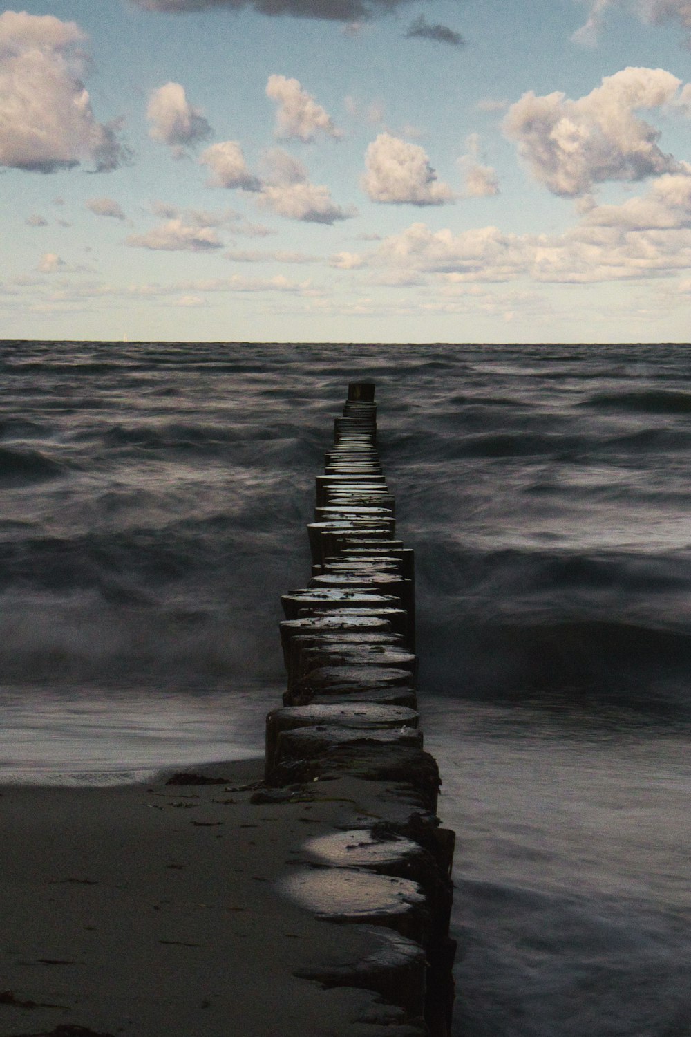 a long pier extending into the ocean under a cloudy sky