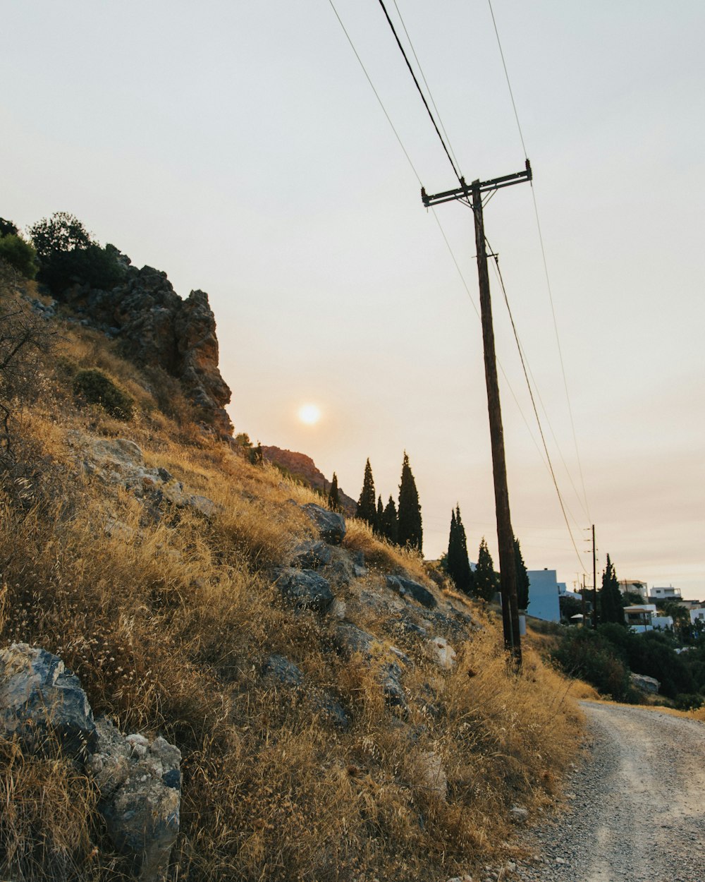 a telephone pole sitting on the side of a dirt road