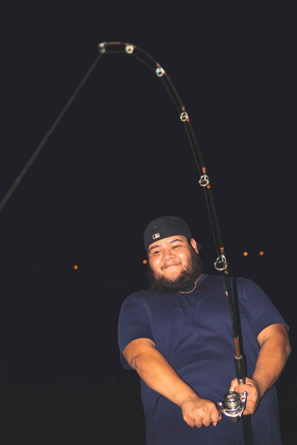 Un homme tenant une canne à pêche et souriant à la caméra