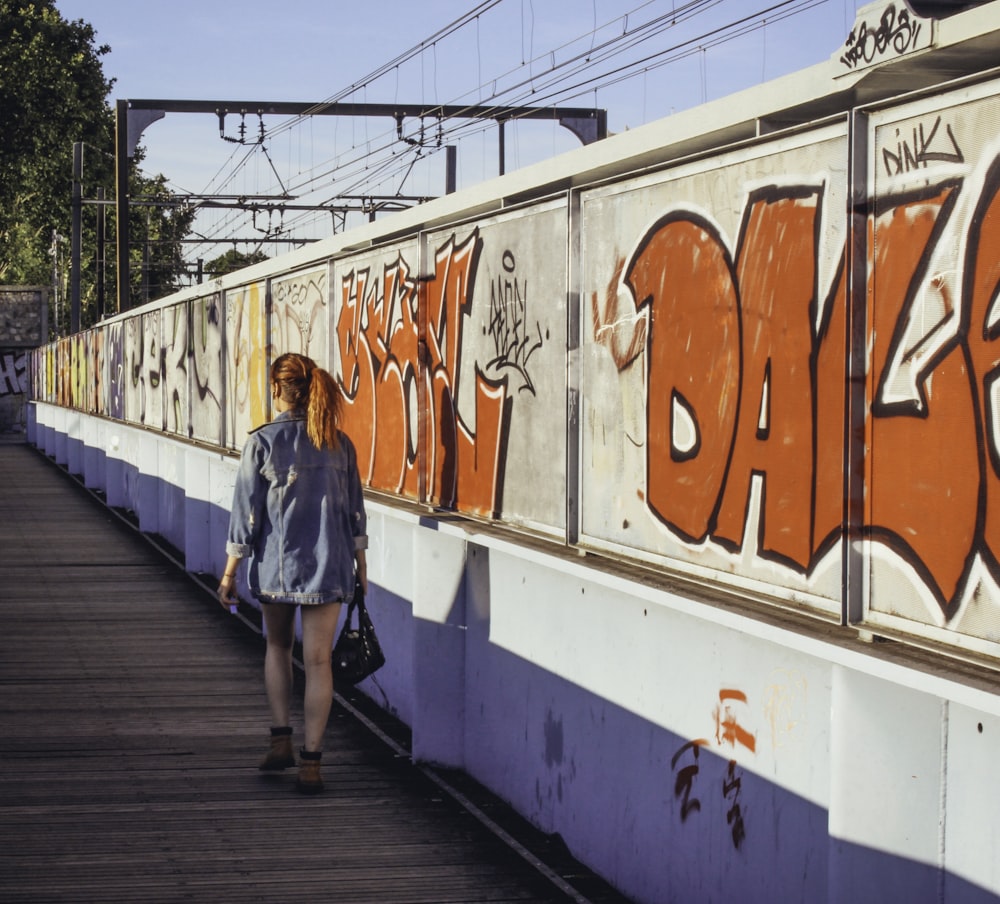 a woman walking down a sidewalk next to a train