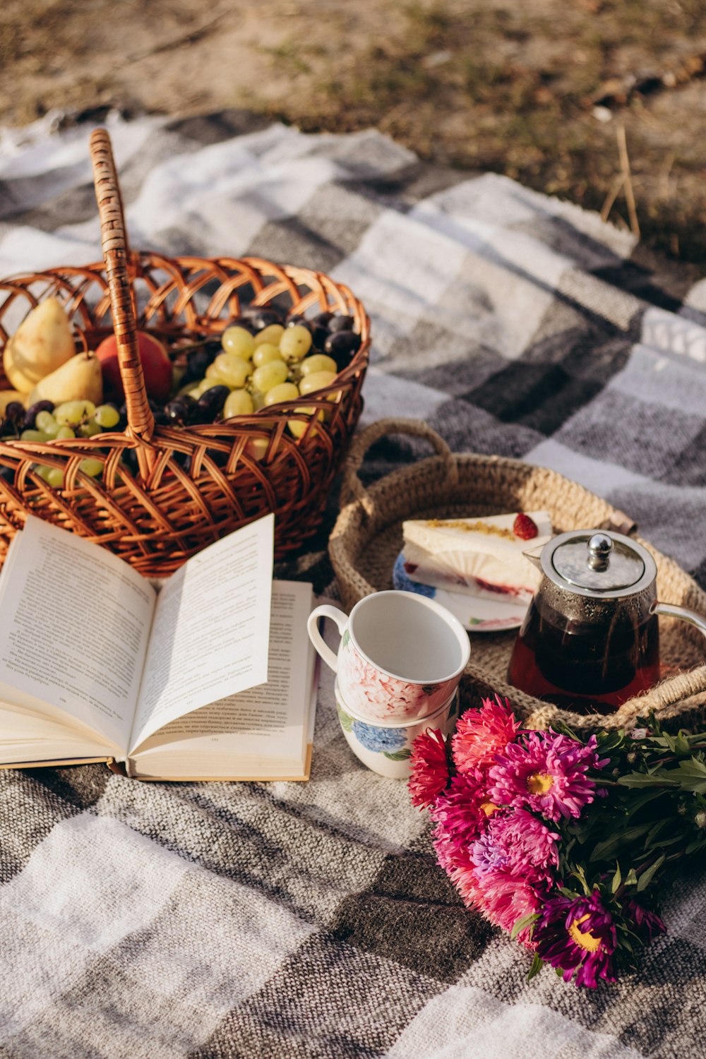 a basket of fruit sitting on top of a blanket next to a cup of coffee