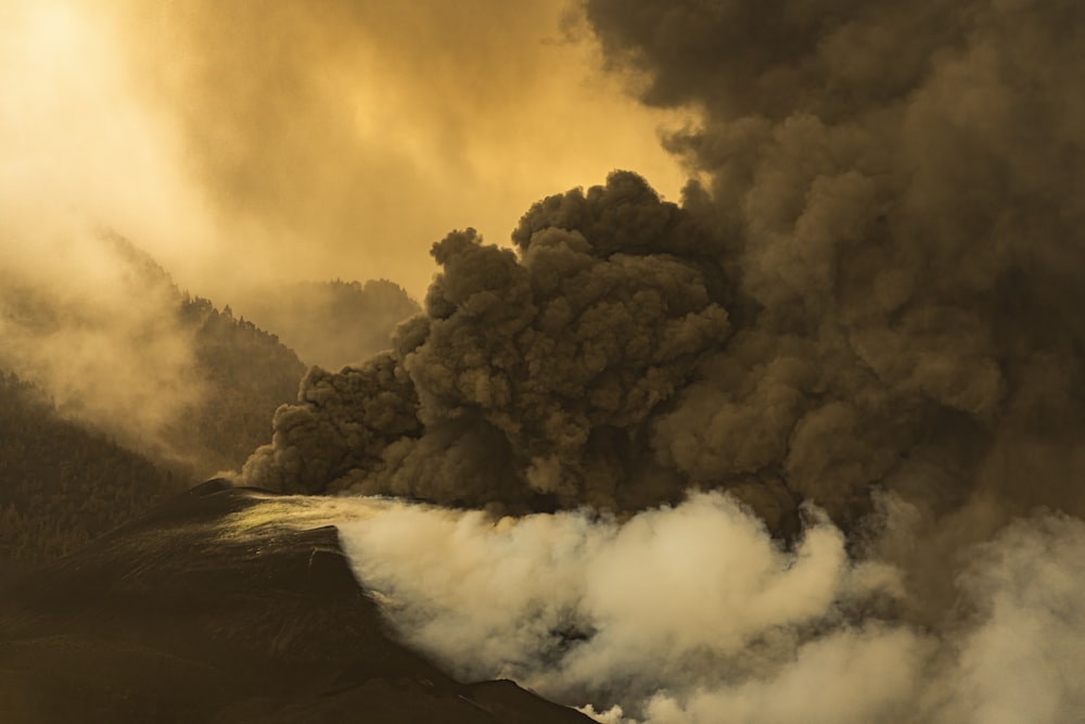 a large plume of smoke billowing out of a mountain