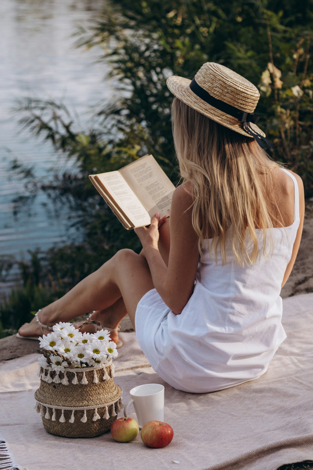 a woman sitting on a blanket reading a book