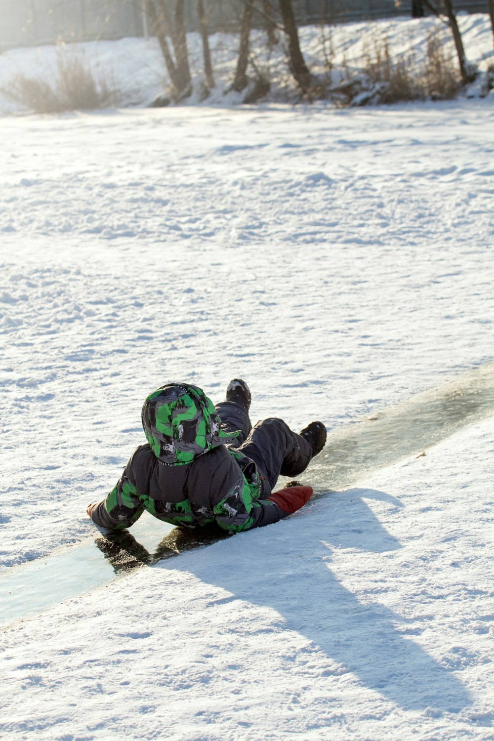 Ein Kind liegt auf einem Snowboard im Schnee