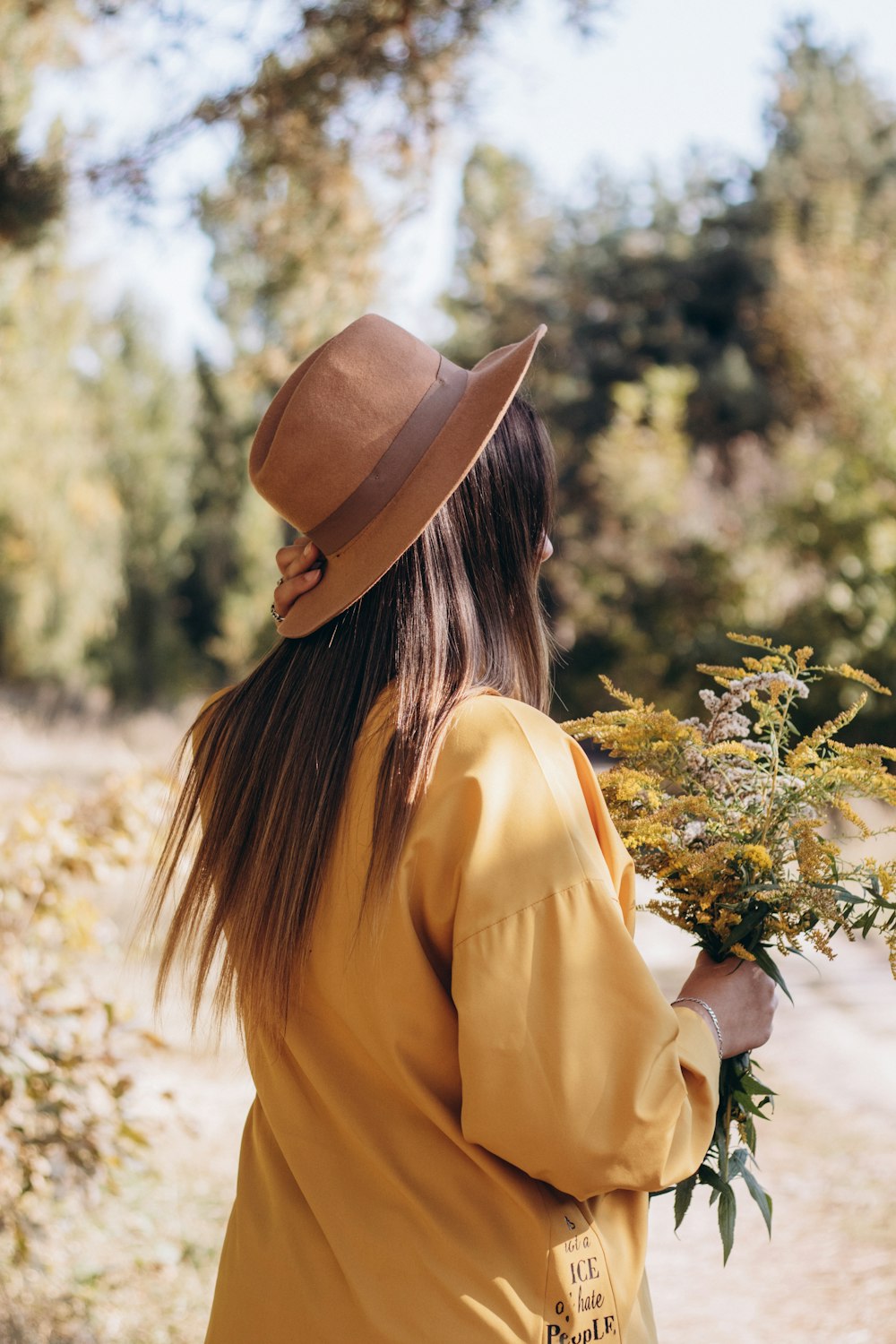 a woman in a hat holding a bouquet of flowers