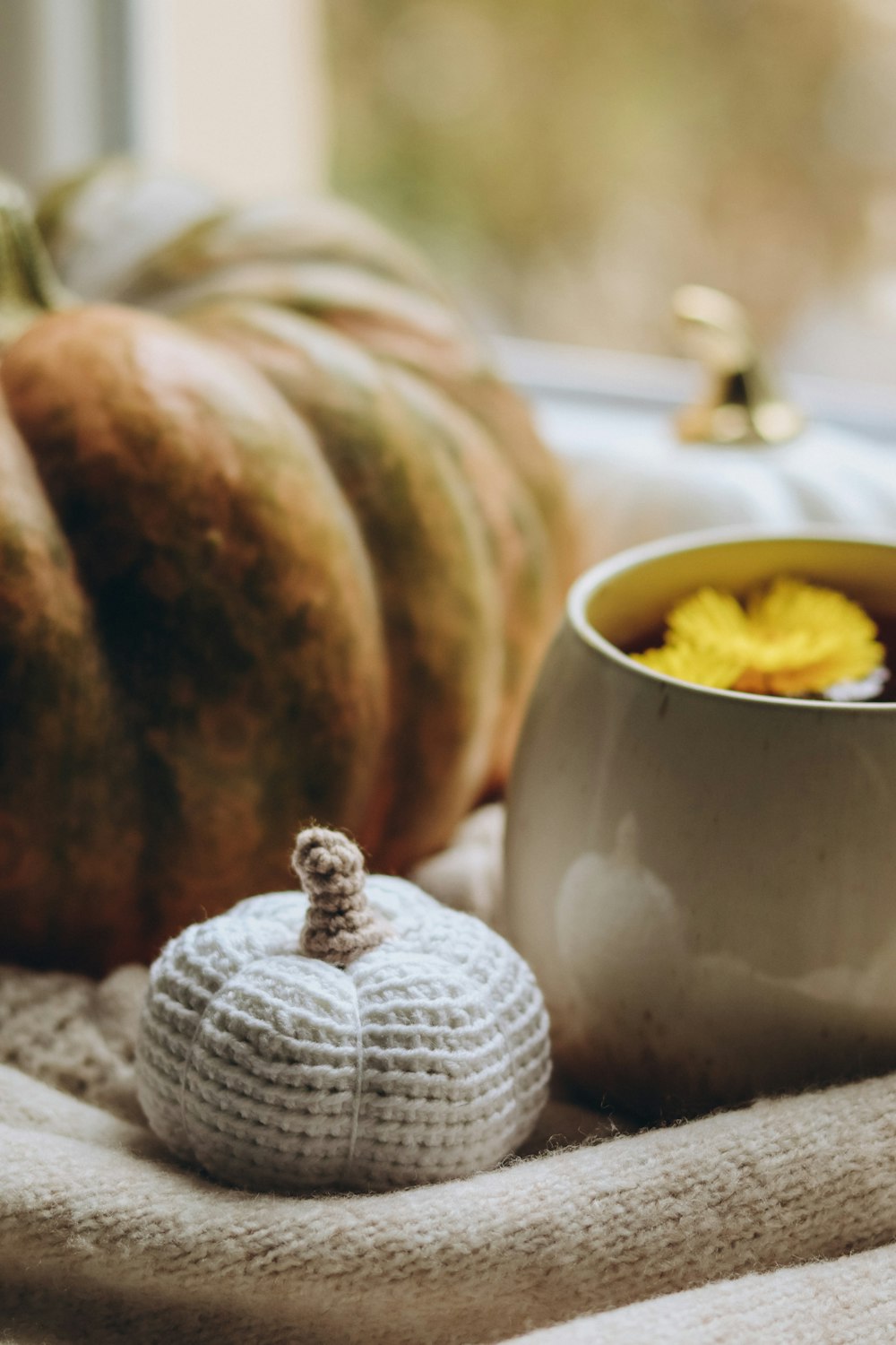 a cup of coffee next to a crocheted pumpkin