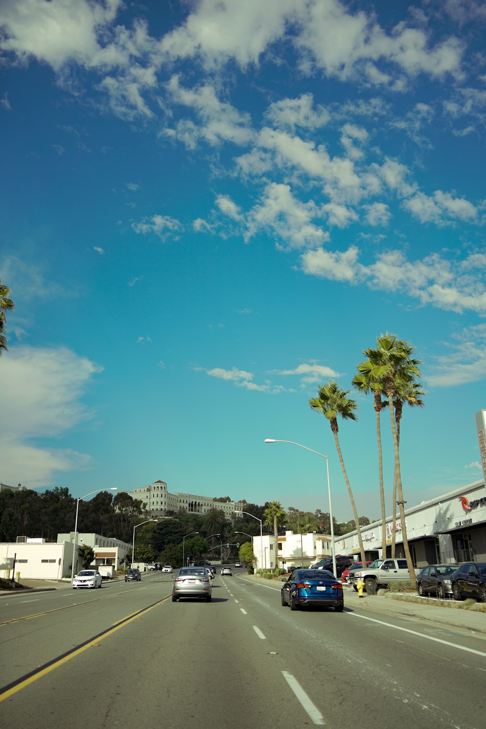 a car driving down a street next to palm trees