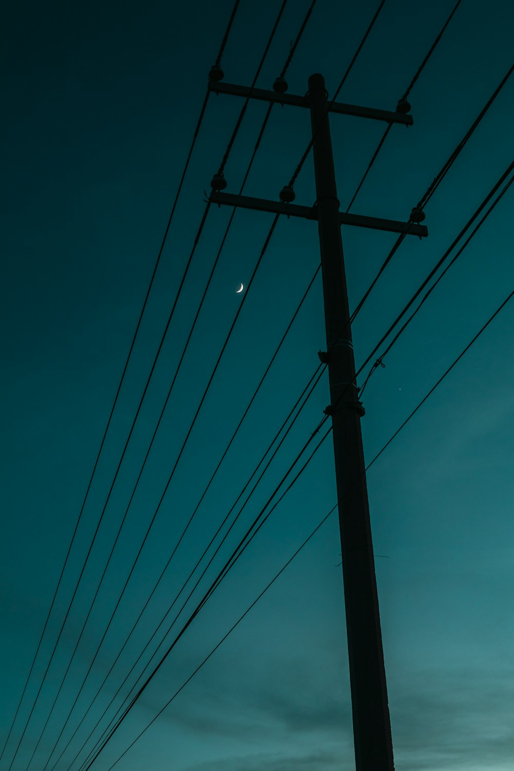 a telephone pole with a moon in the sky