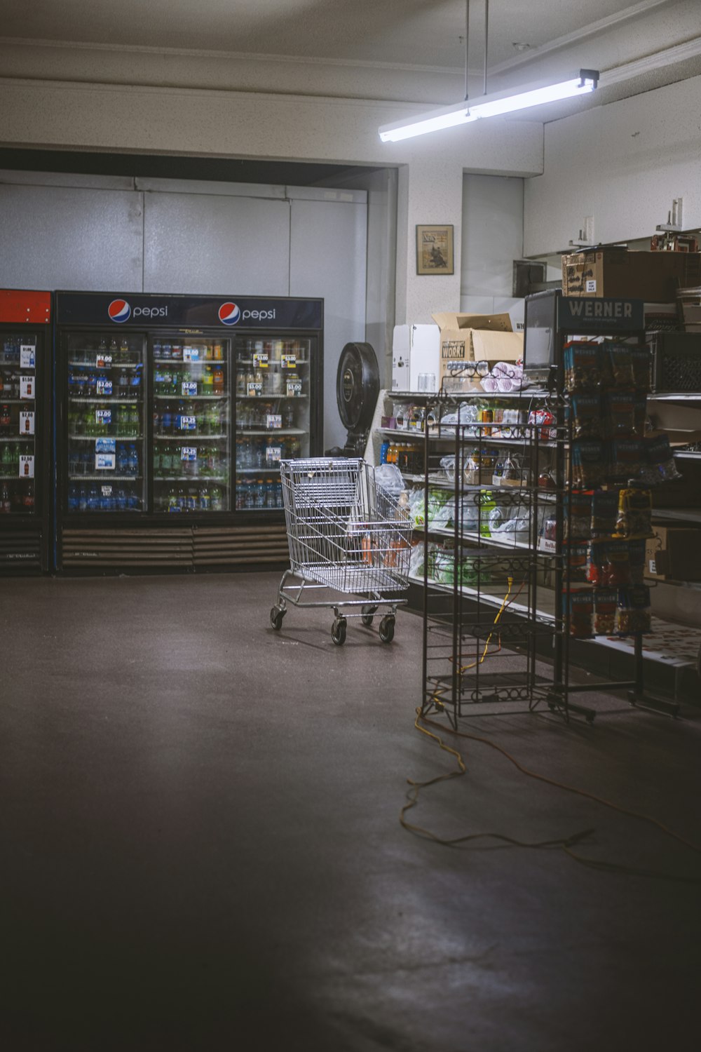 a grocery store with a shopping cart in the middle of the room