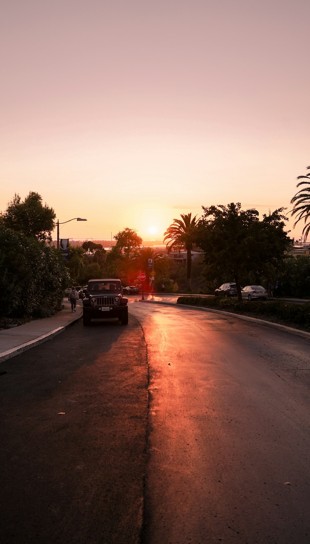 the sun is setting over a street with cars