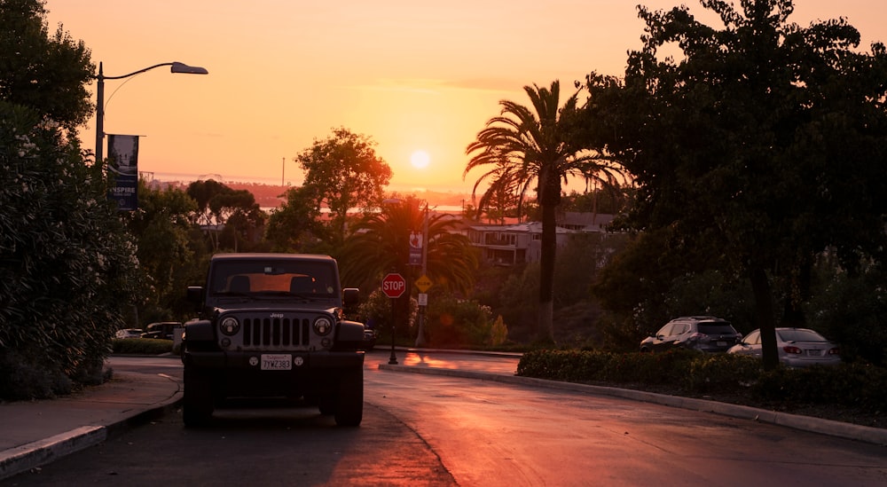 a jeep driving down a street at sunset