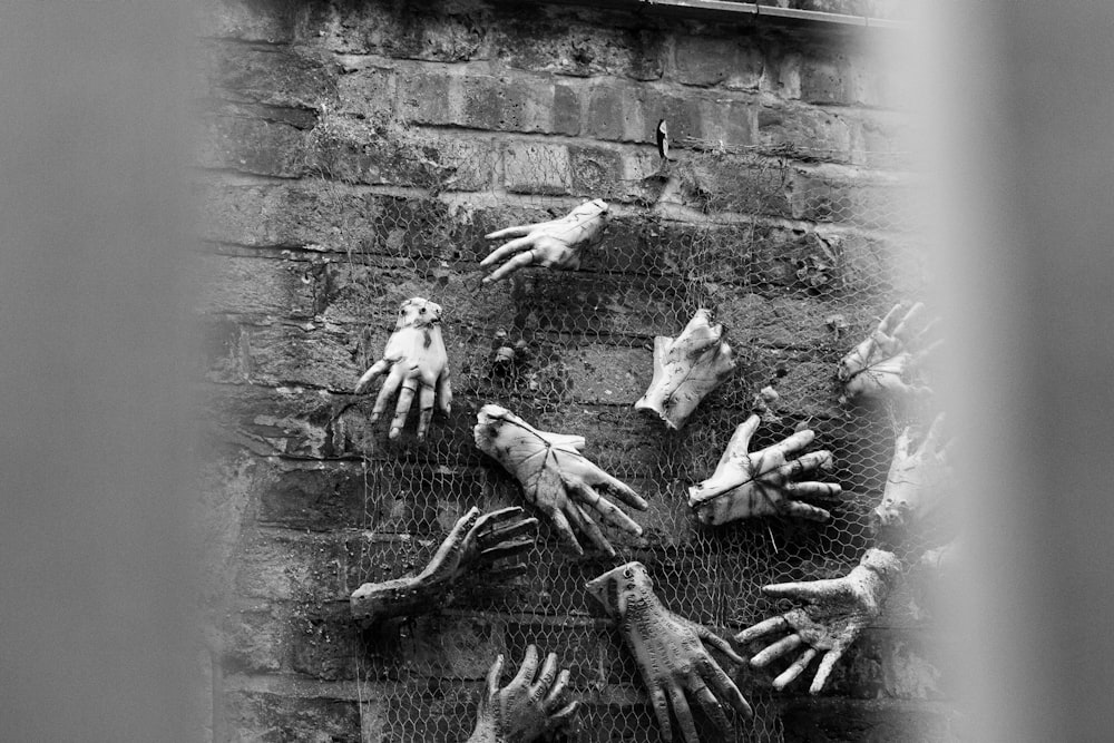 a group of hands reaching out of a brick wall