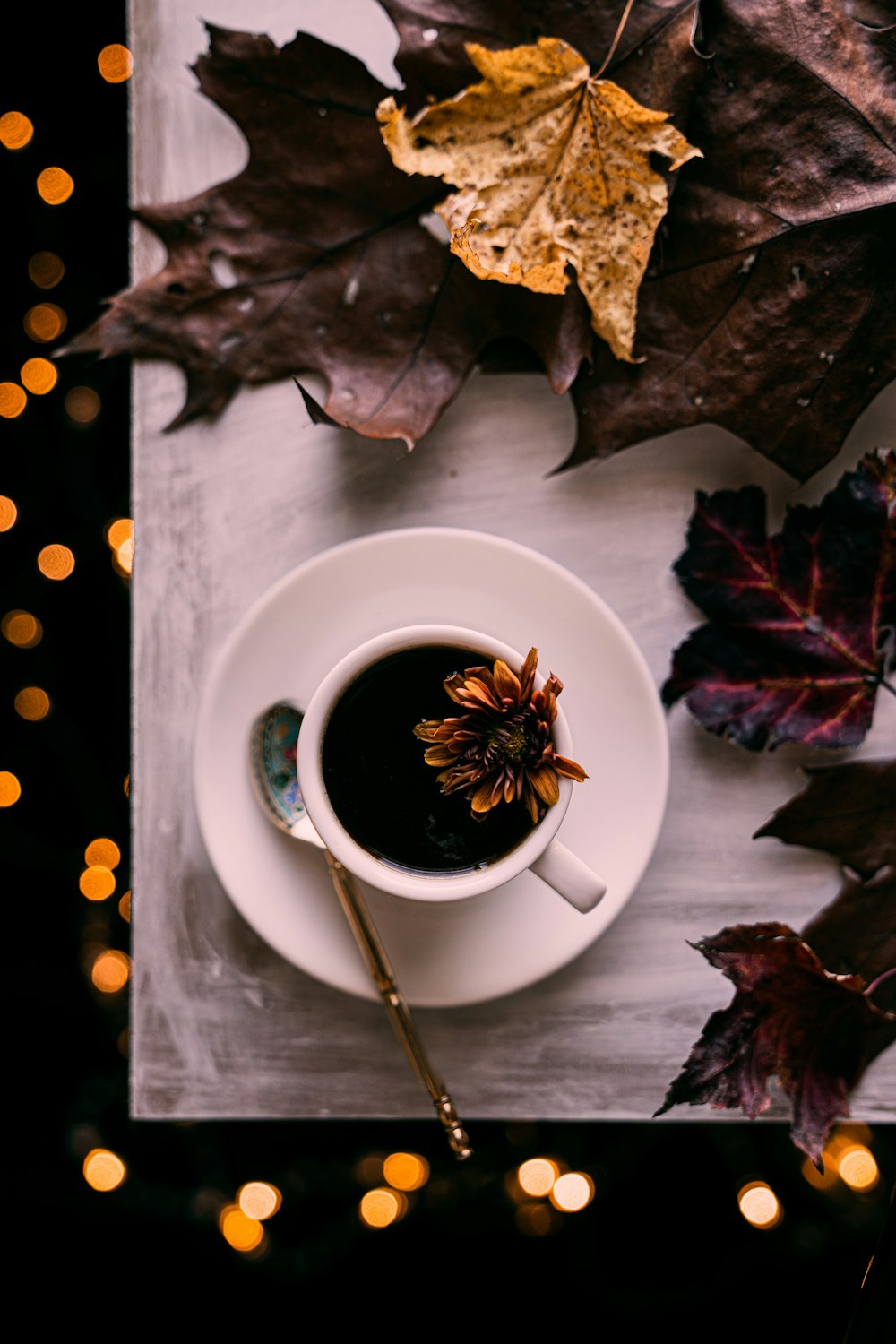 a cup of coffee on a table with autumn leaves