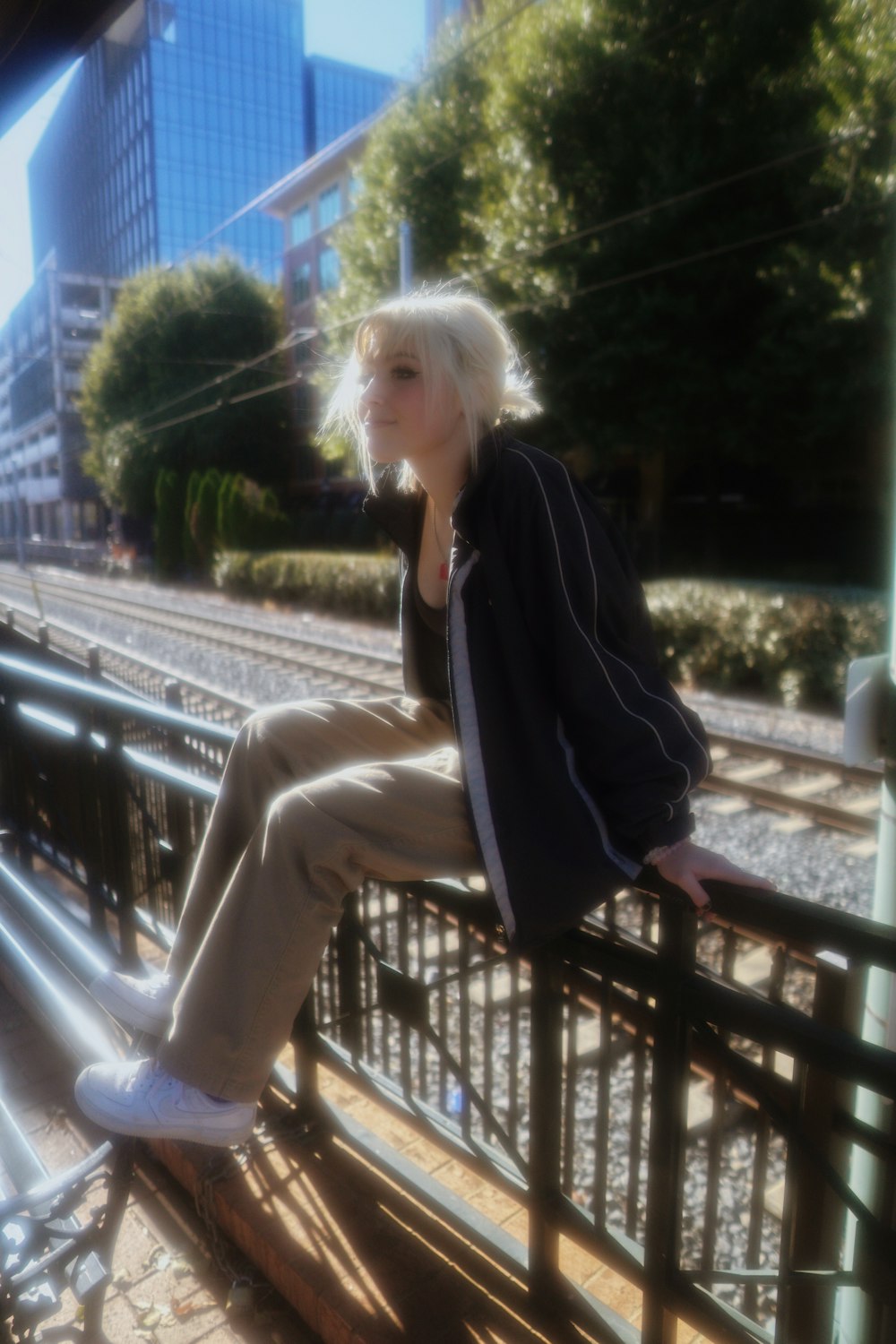 a woman sitting on a rail next to a train track