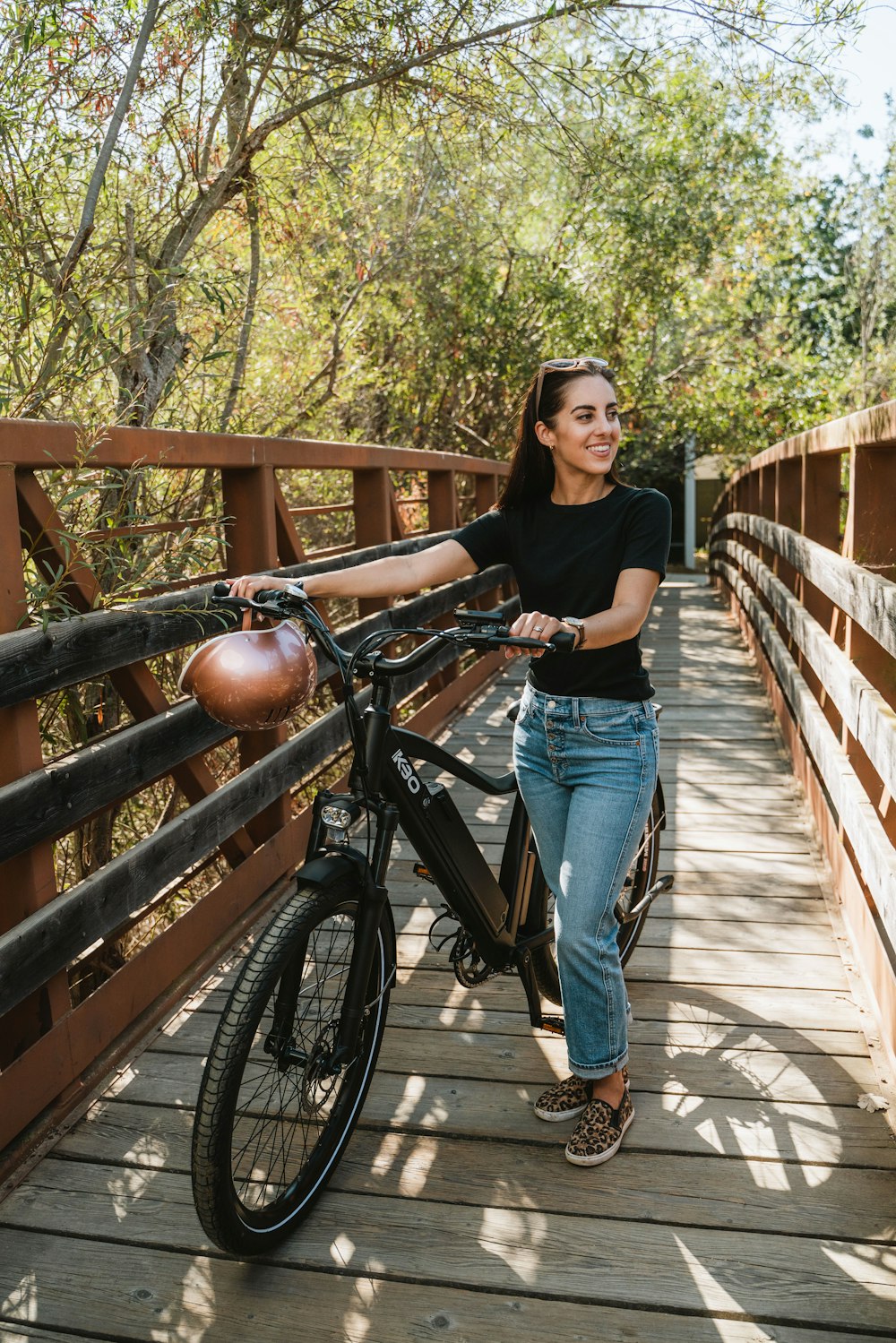 a woman standing on a bridge with a bicycle