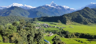 a scenic view of a green valley with mountains in the background
