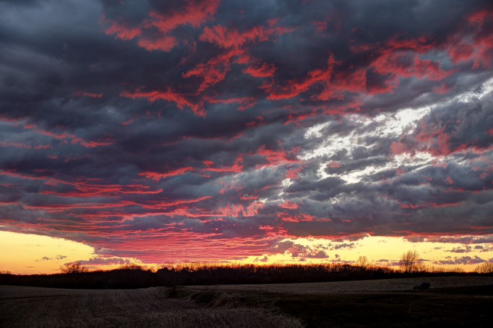 a sunset with clouds in the sky over a field