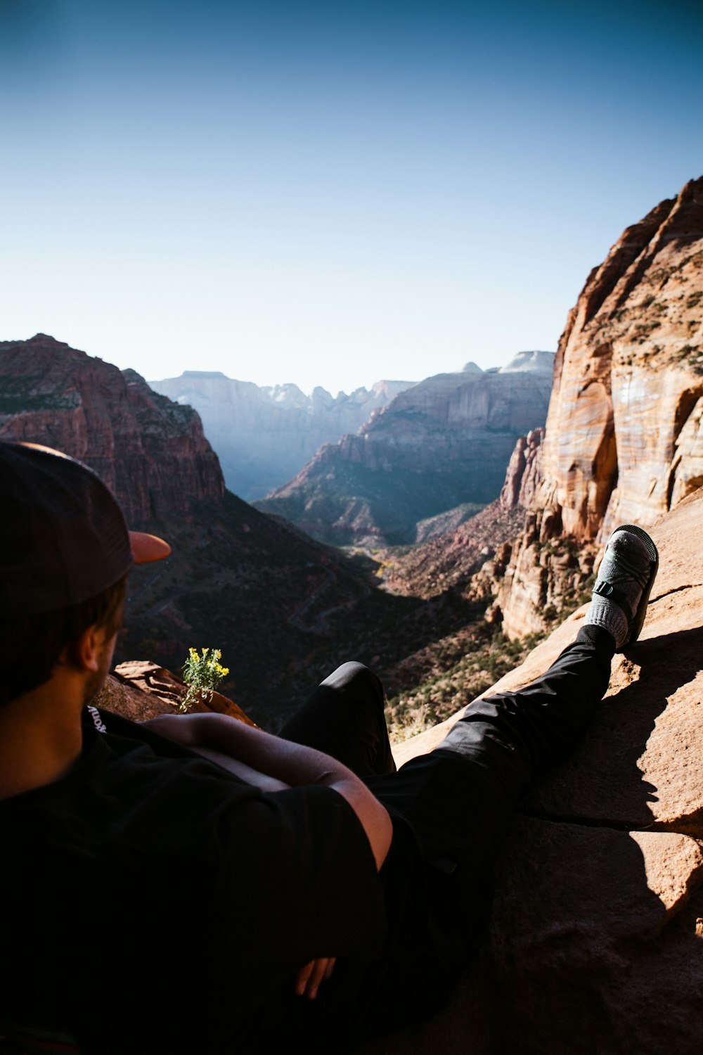 a man sitting on a cliff overlooking a valley