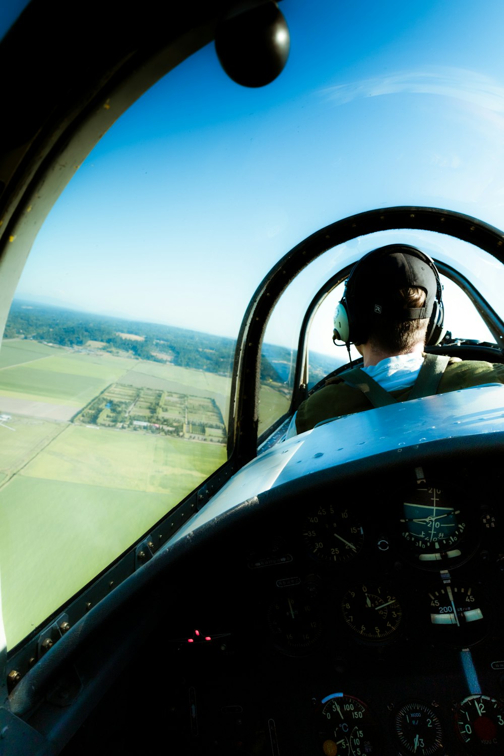 a man flying a small airplane over a lush green field