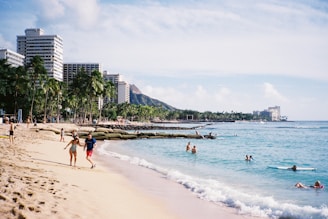 a group of people walking along a beach next to the ocean
