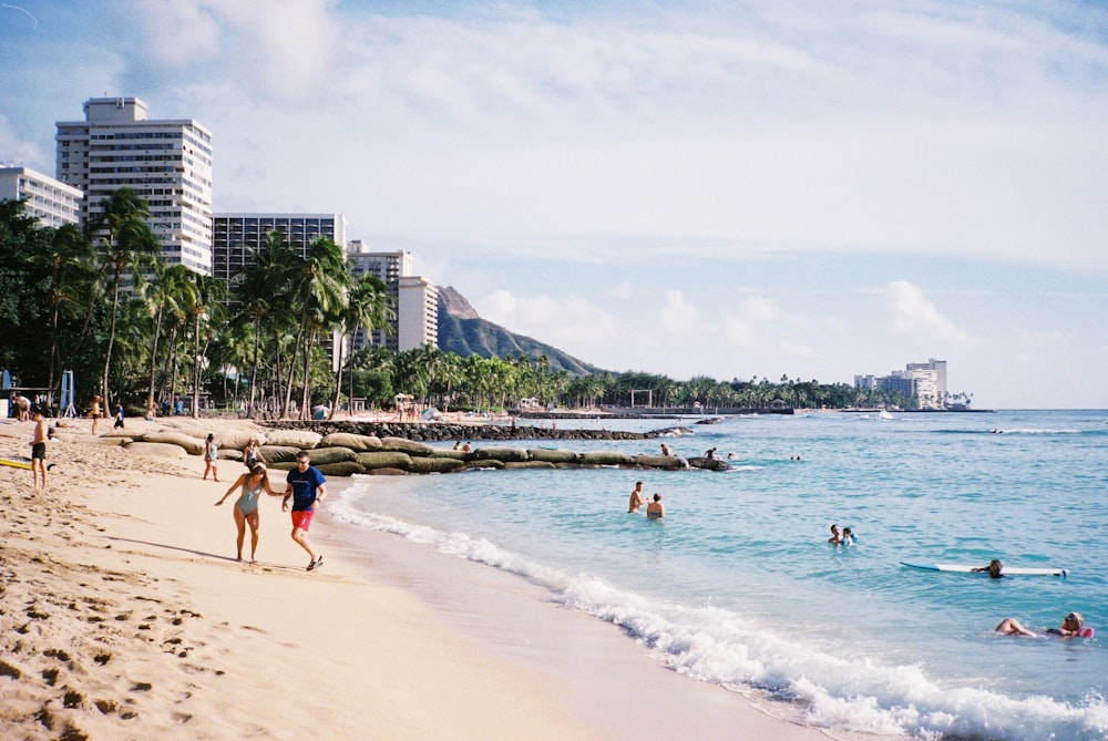 a group of people walking along a beach next to the ocean