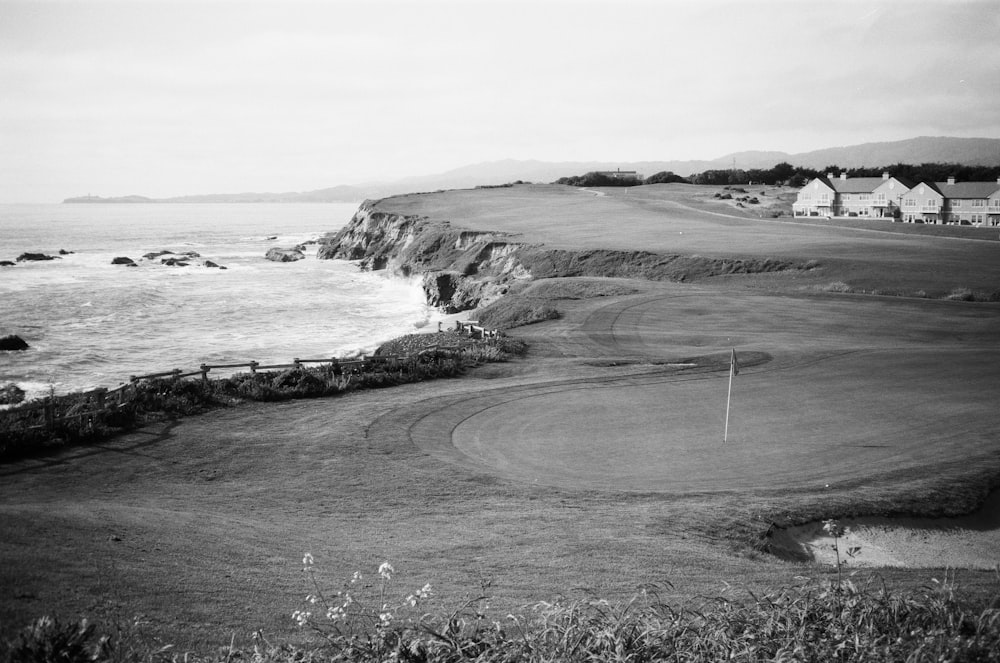a black and white photo of a golf course near the ocean