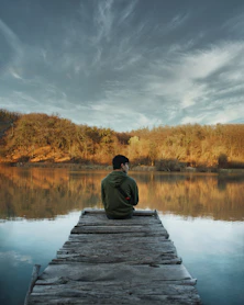 a man sitting on a dock looking at the water