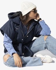 A casual outfit featuring layered jackets and crisp white sneakers.