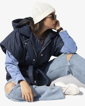 A casual outfit featuring layered jackets and crisp white sneakers.