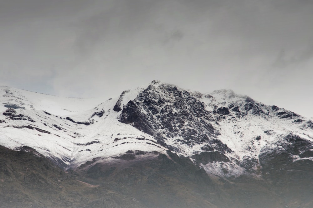 a mountain covered in snow under a cloudy sky