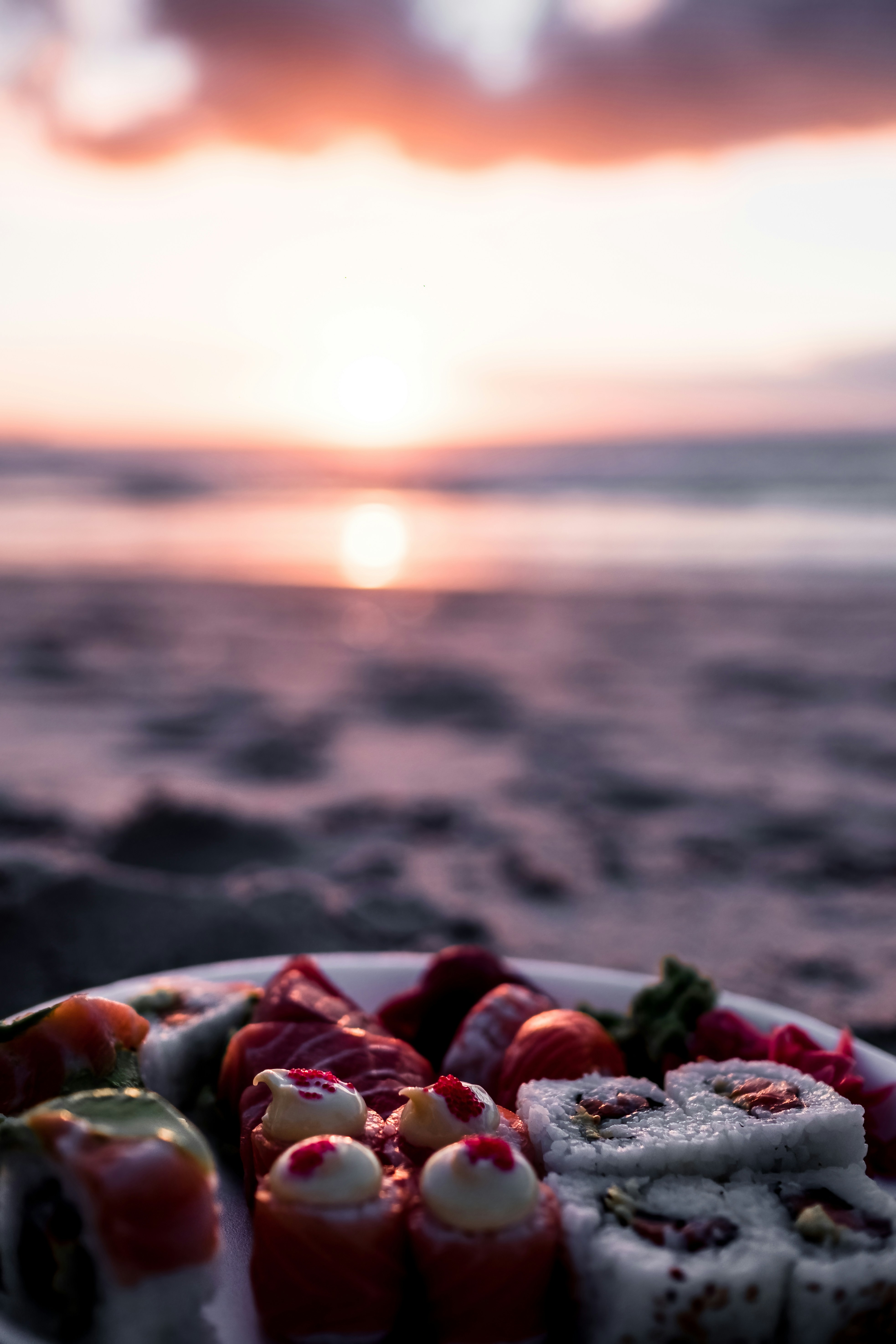 a plate of sushi on a beach at sunset