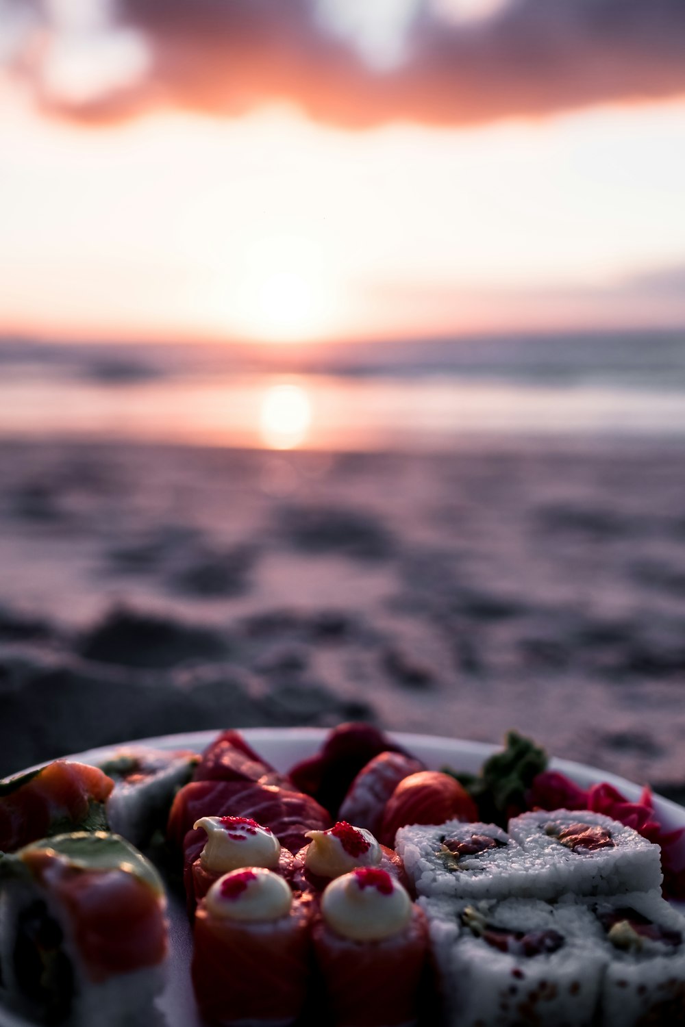 a plate of sushi on a beach at sunset