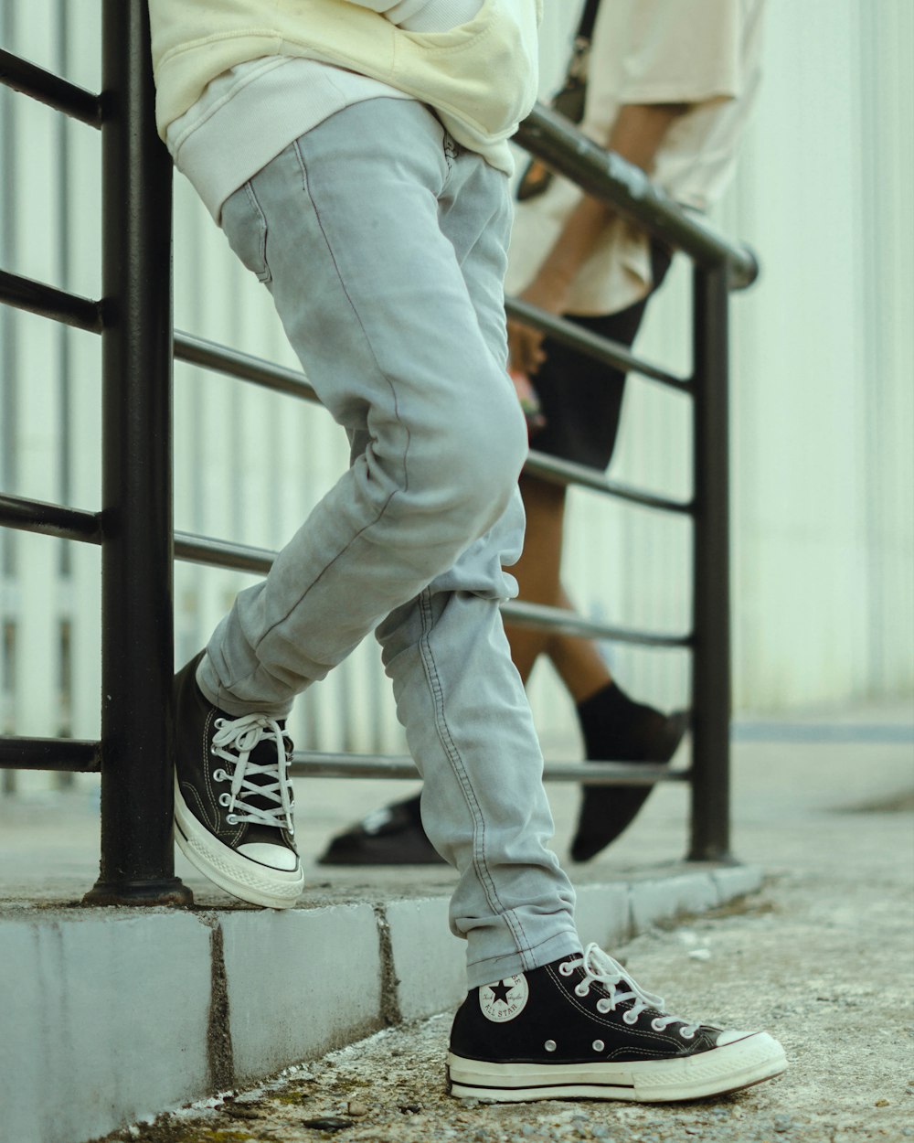 a person leaning against a rail with their legs crossed