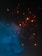 Sparks of bright orange light dance against a dark background, contrasting with a plume of blue smoke swirling upward. The scene conveys movement and energy, with the glowing particles creating a dynamic visual effect.