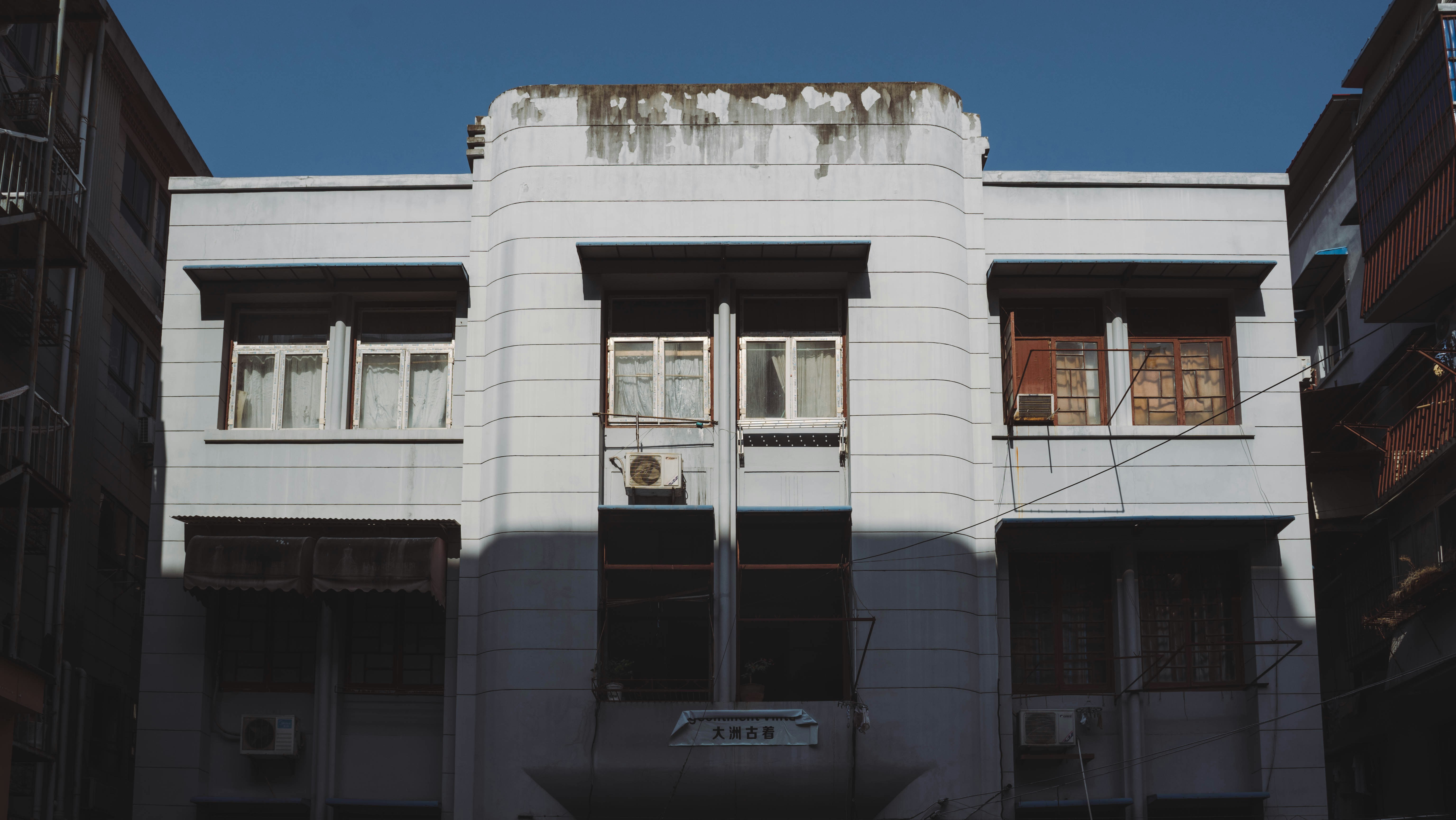 a tall white building with windows and a sky background