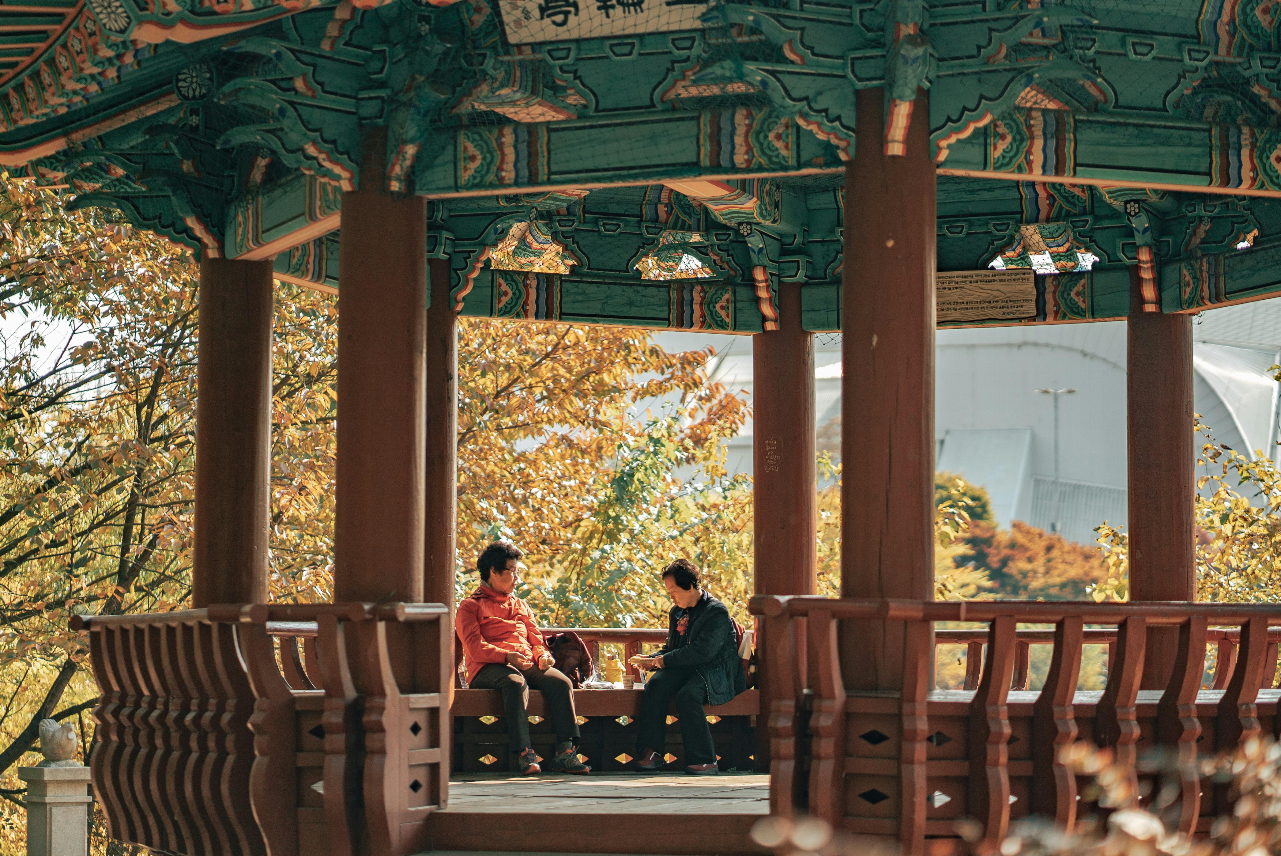 a couple of people sitting on top of a wooden gazebo, 