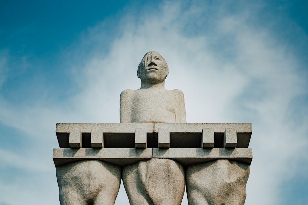 Una estatua de un hombre sentado encima de un banco