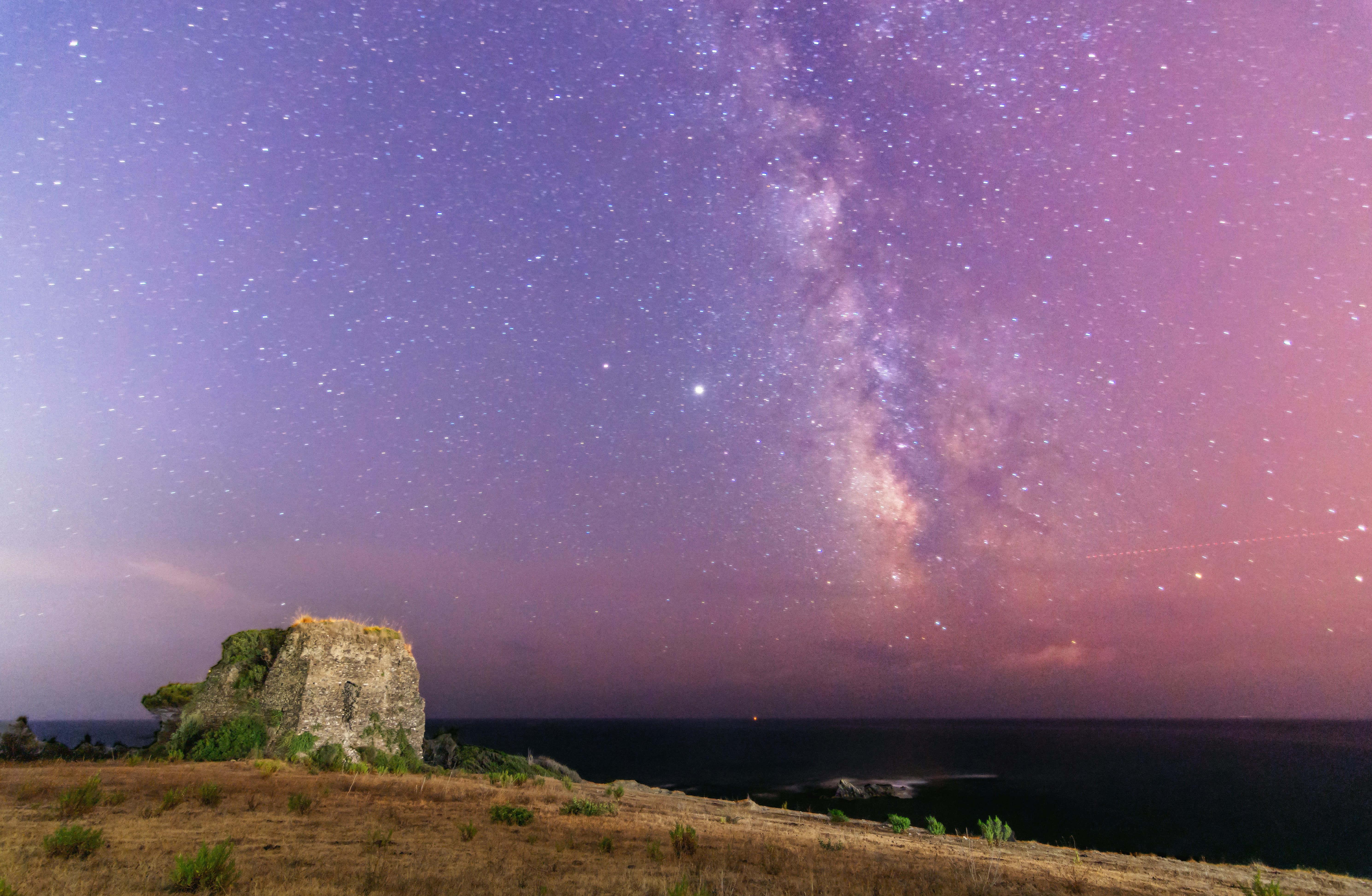 the night sky is filled with stars above a rocky outcropping