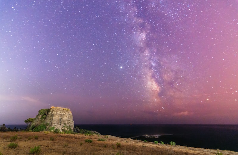 the night sky is filled with stars above a rocky outcropping