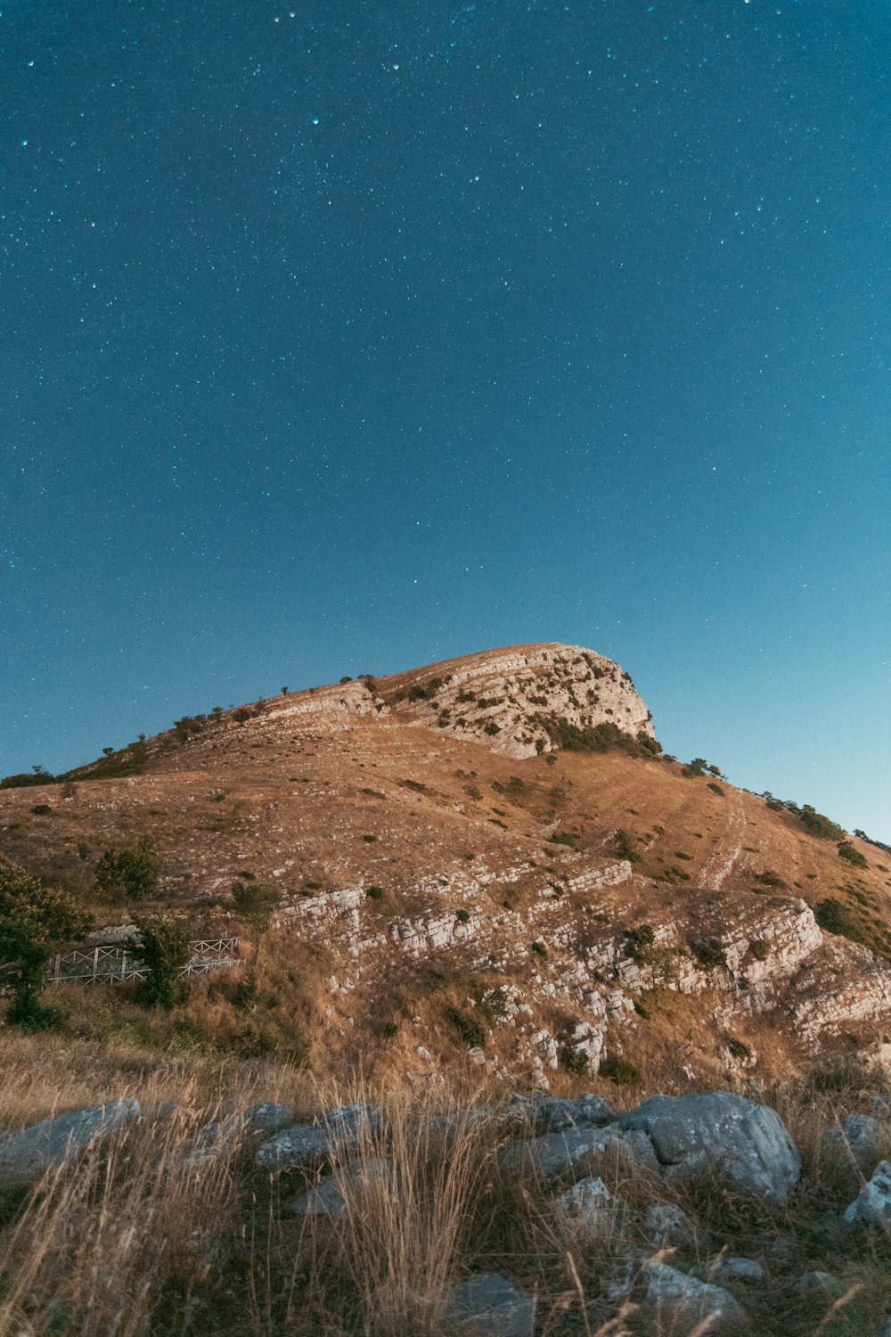 a hill with grass and rocks under a blue sky