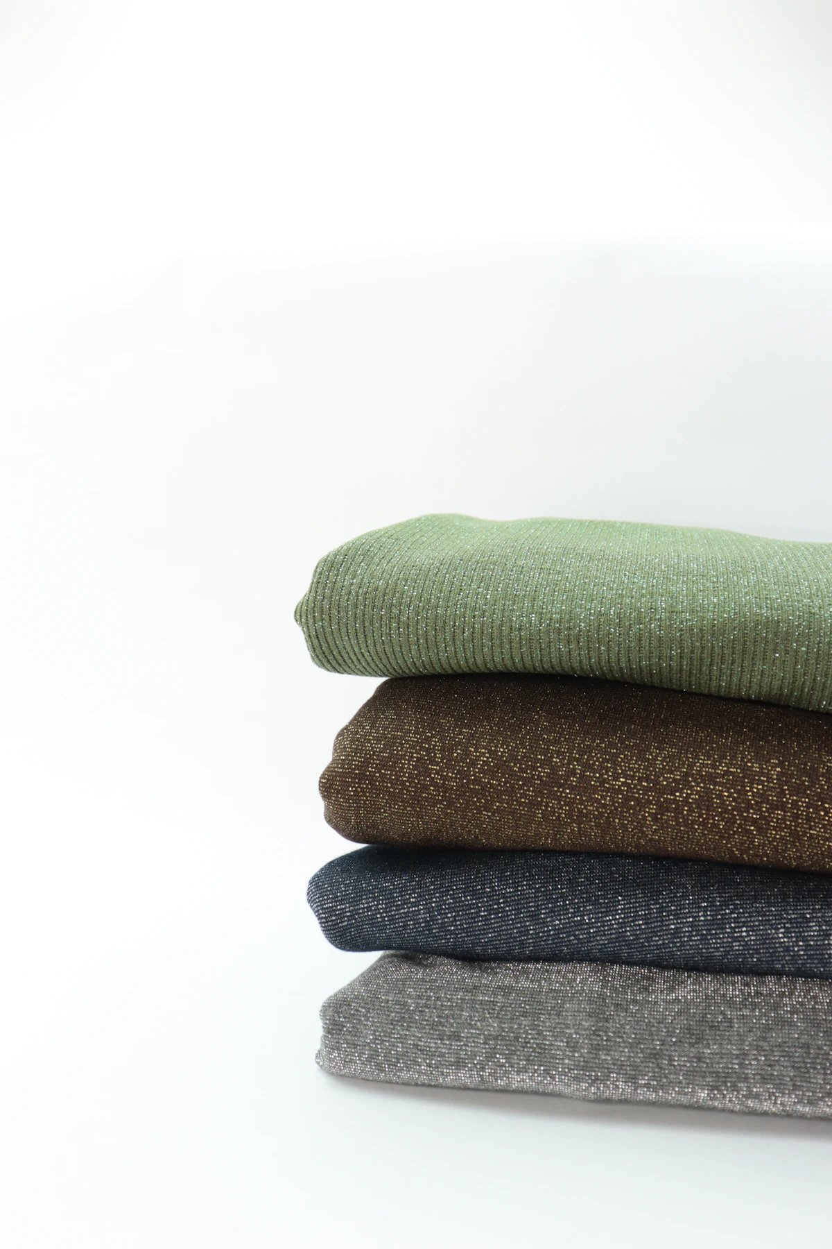 Stack of folded woven blankets displaying different colors and textures
