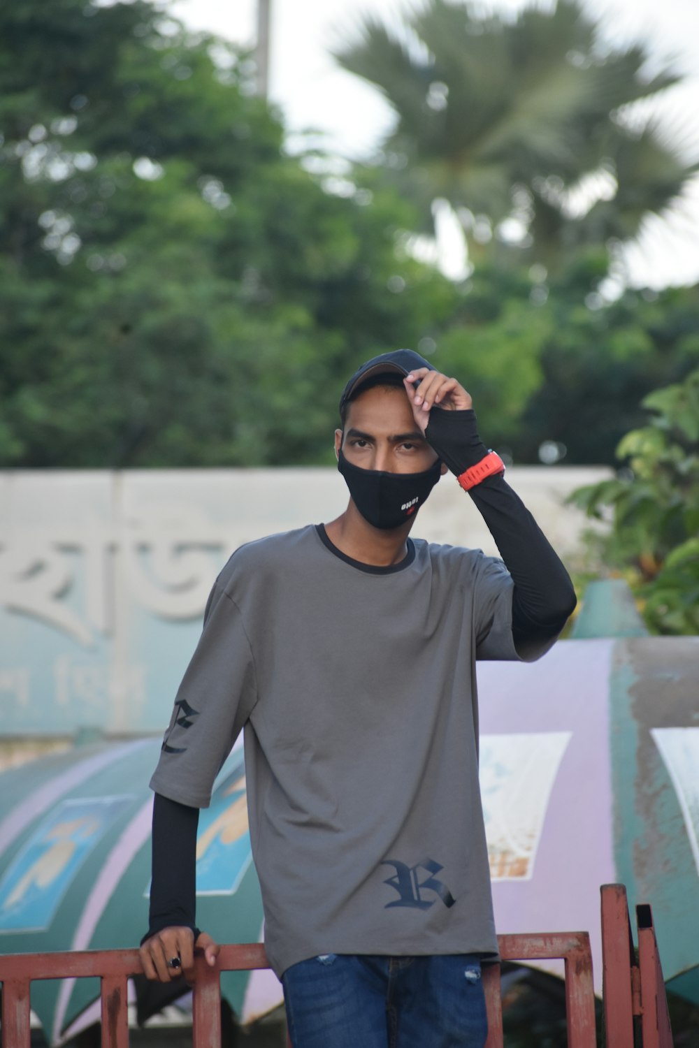 a man wearing a face mask standing next to a fence