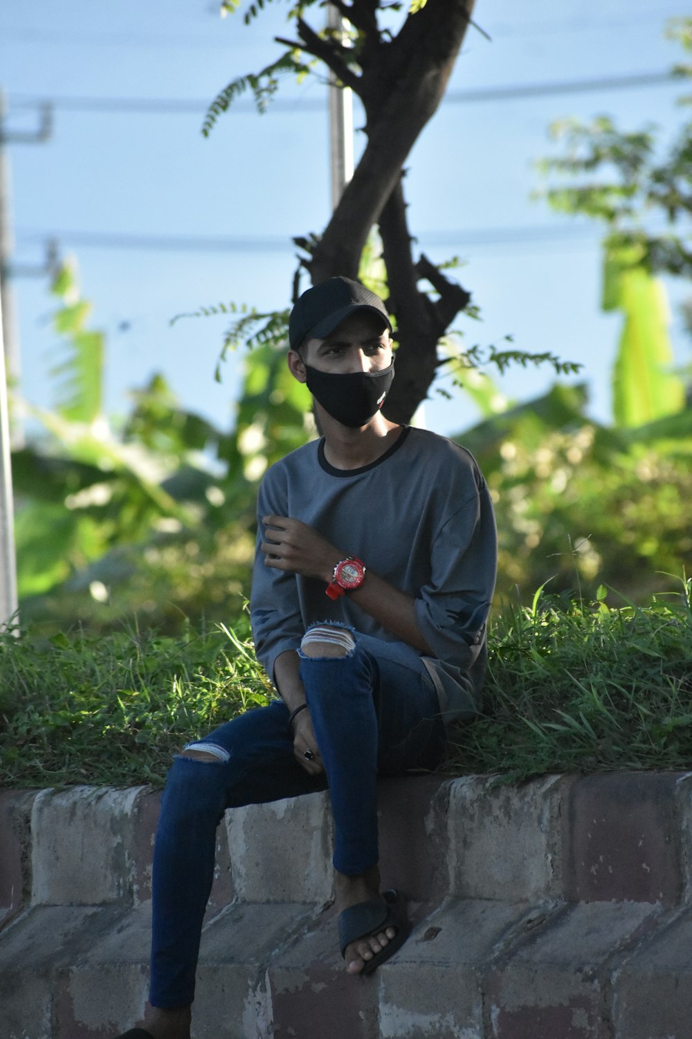 a man wearing a mask sitting on a brick wall
