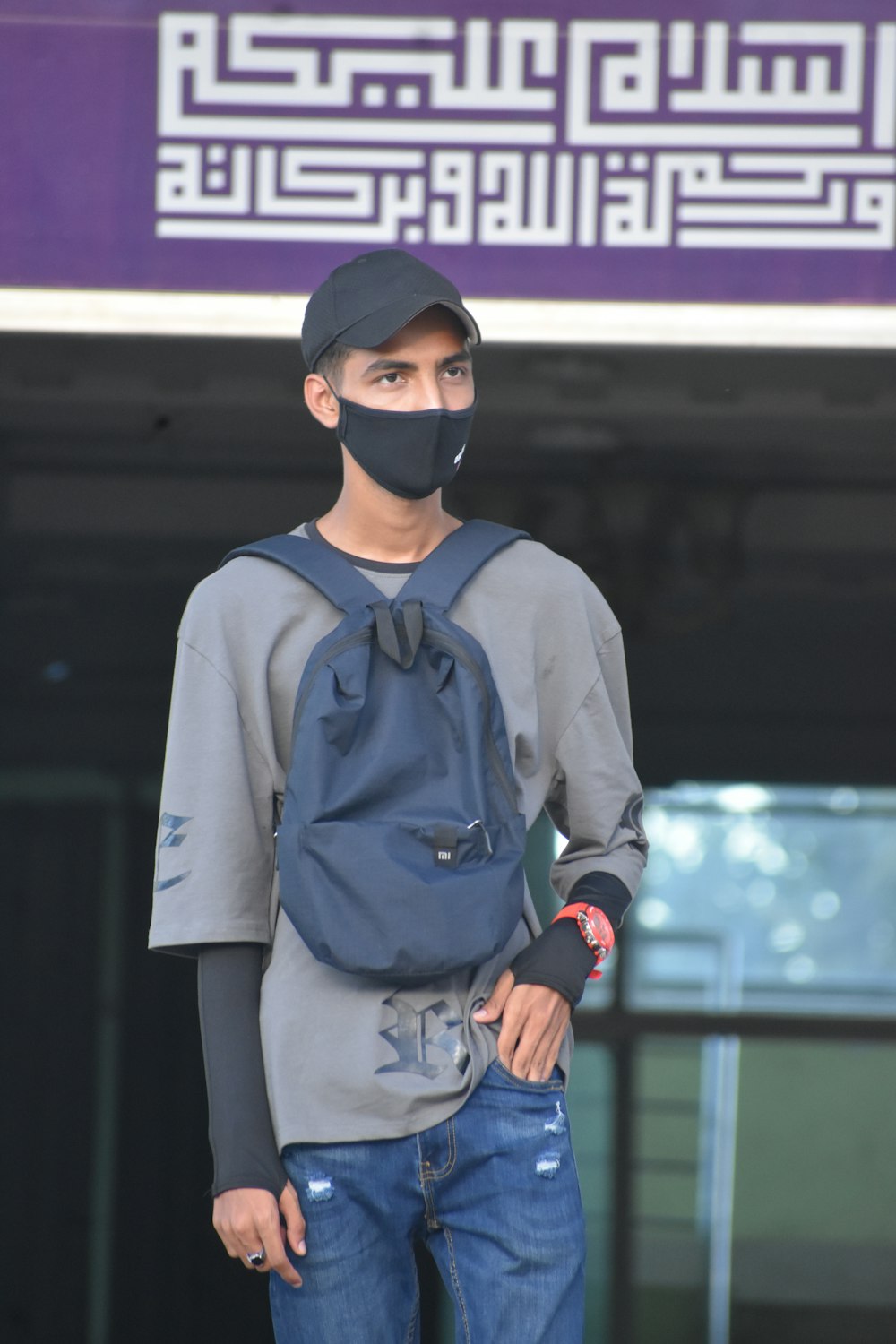 a man wearing a face mask standing in front of a building