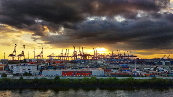 A modern port with automated cranes and digital control systems at sunset.