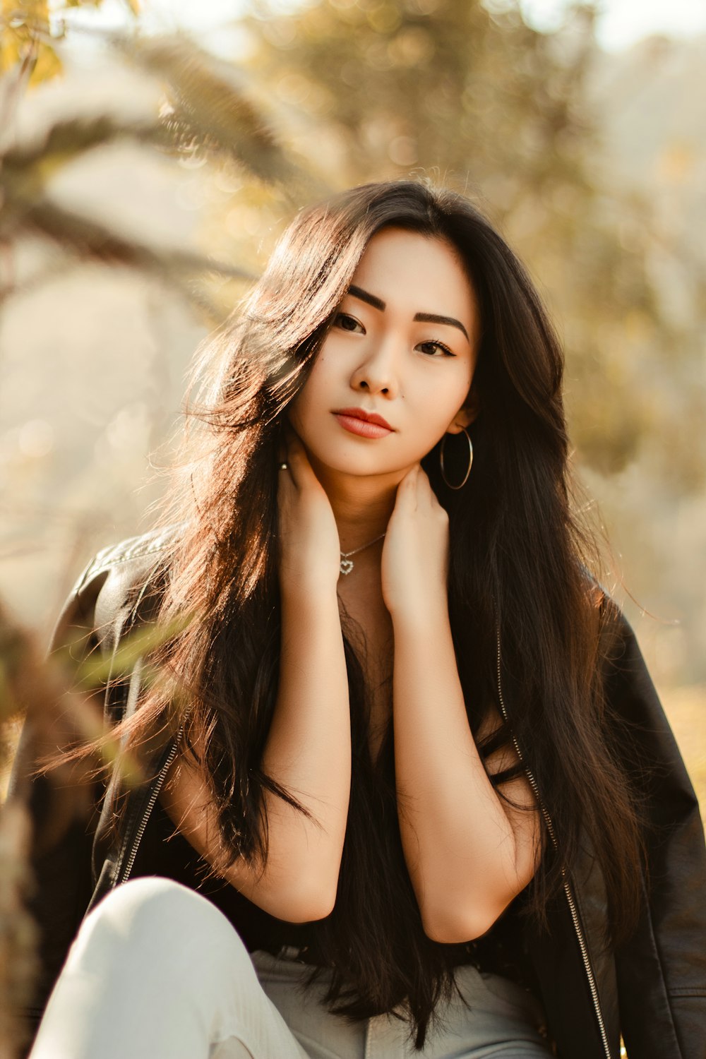 a woman with long hair sitting in a field