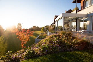 a house with a large lawn and flowers in front of it