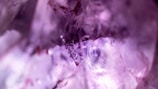 A close-up of a sparkling amethyst crystal on a wooden surface.