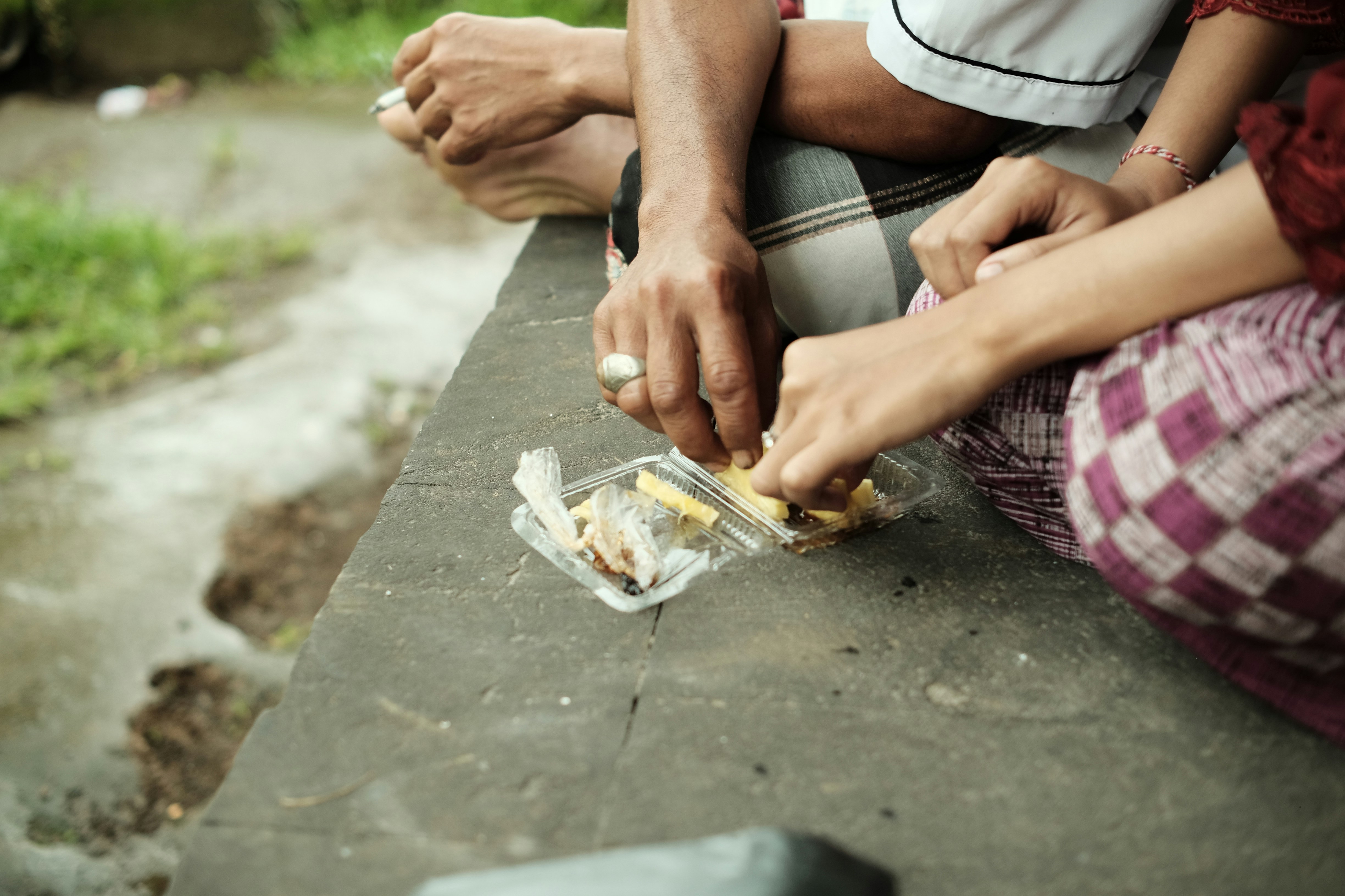 a couple of people sitting on top of a cement bench, 