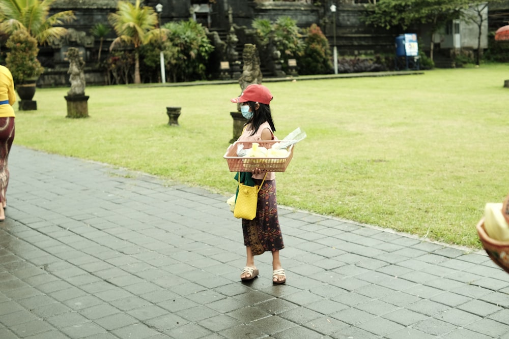 a woman carrying a basket of food in a park